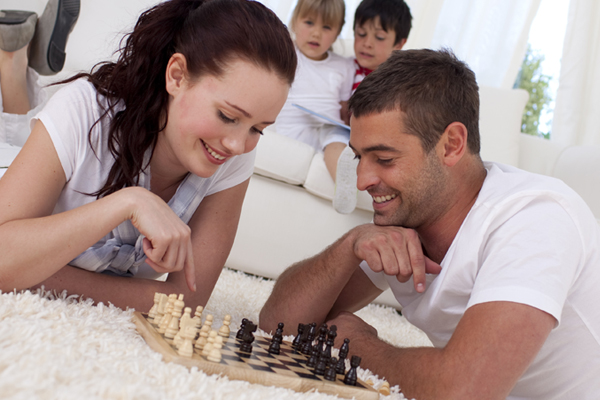 Comfortable family when parents play chess aand children read a book